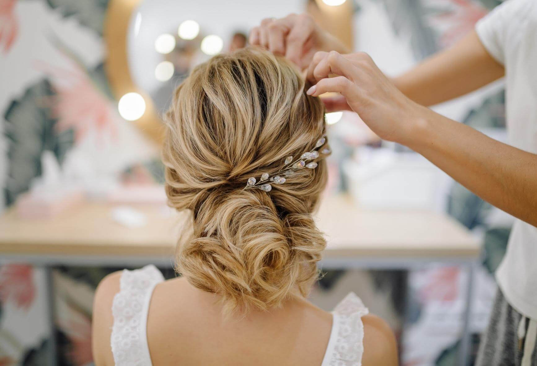 Hair stylist finishing a woman's up-do wedding hairstyle