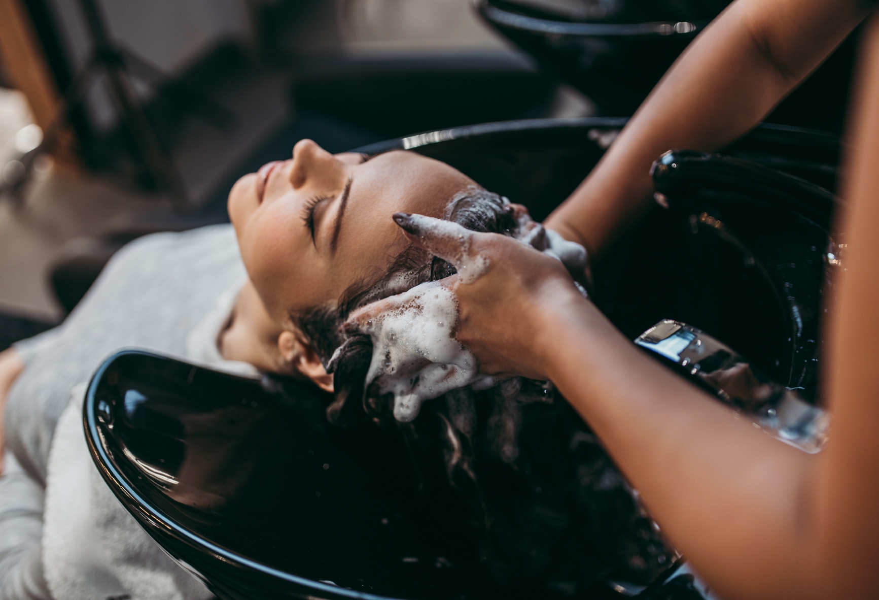 Dark haired woman having her hair washed at the salon